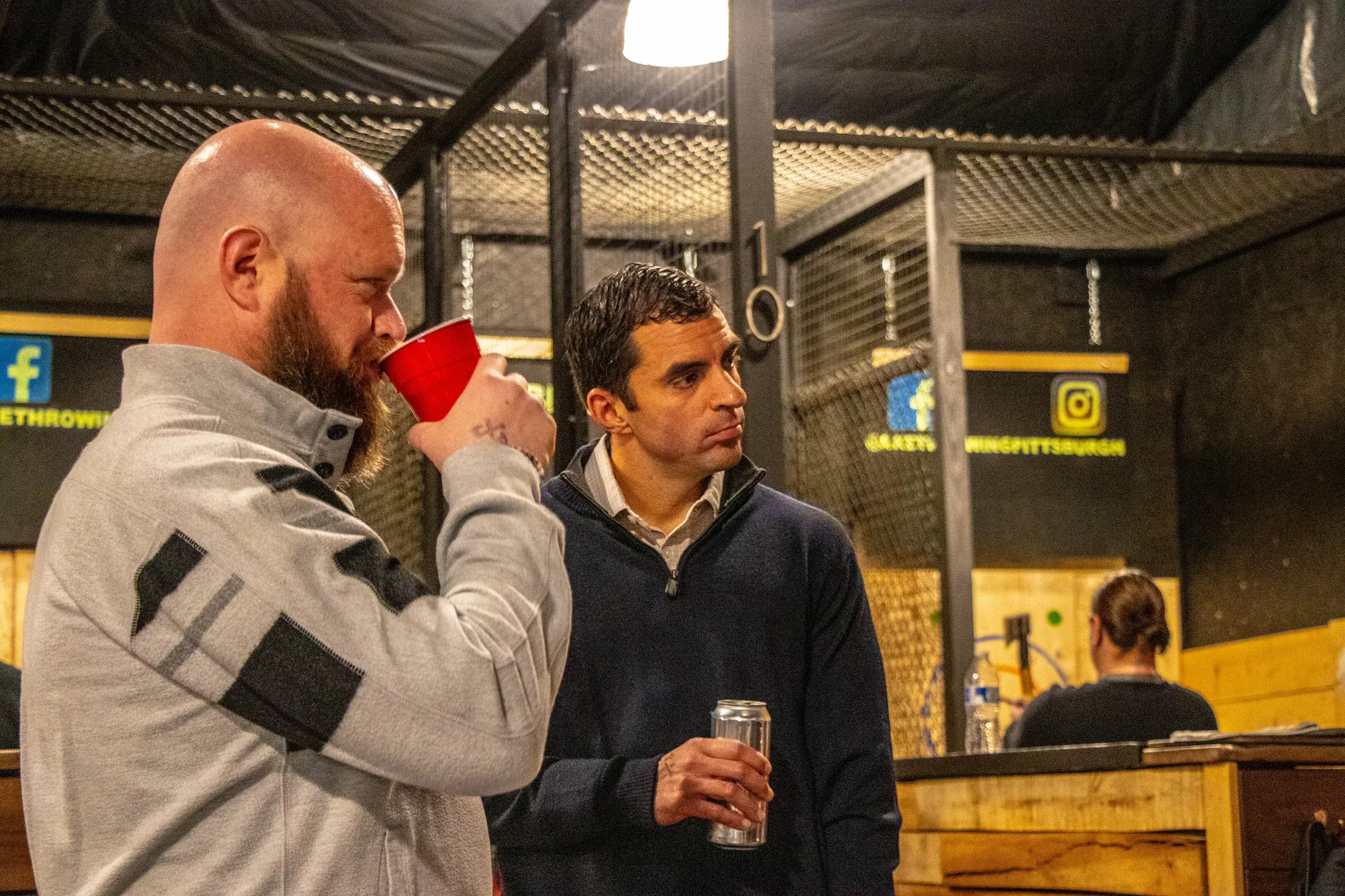 Guests talking over drinks beside the axe lanes